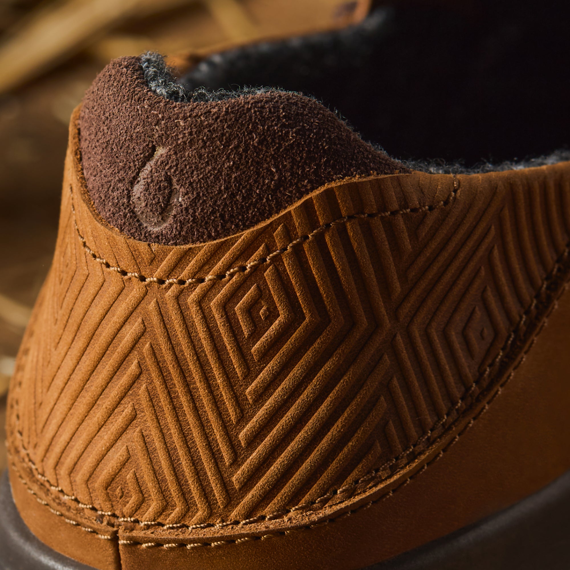 Brown suede boot cuff with geometric quilted pattern and dark fleece lining visible at top.